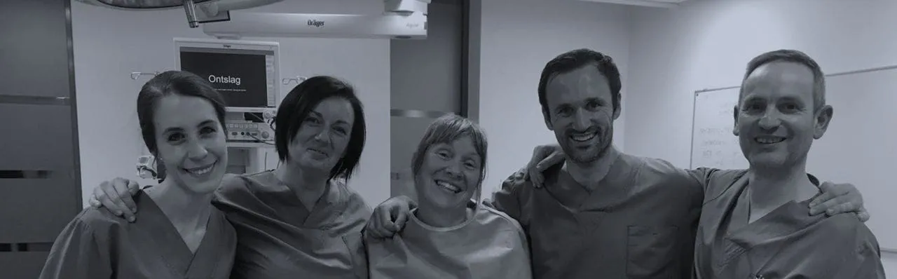 Tim and four others in surgical scrubs, arm in arm in an operating room