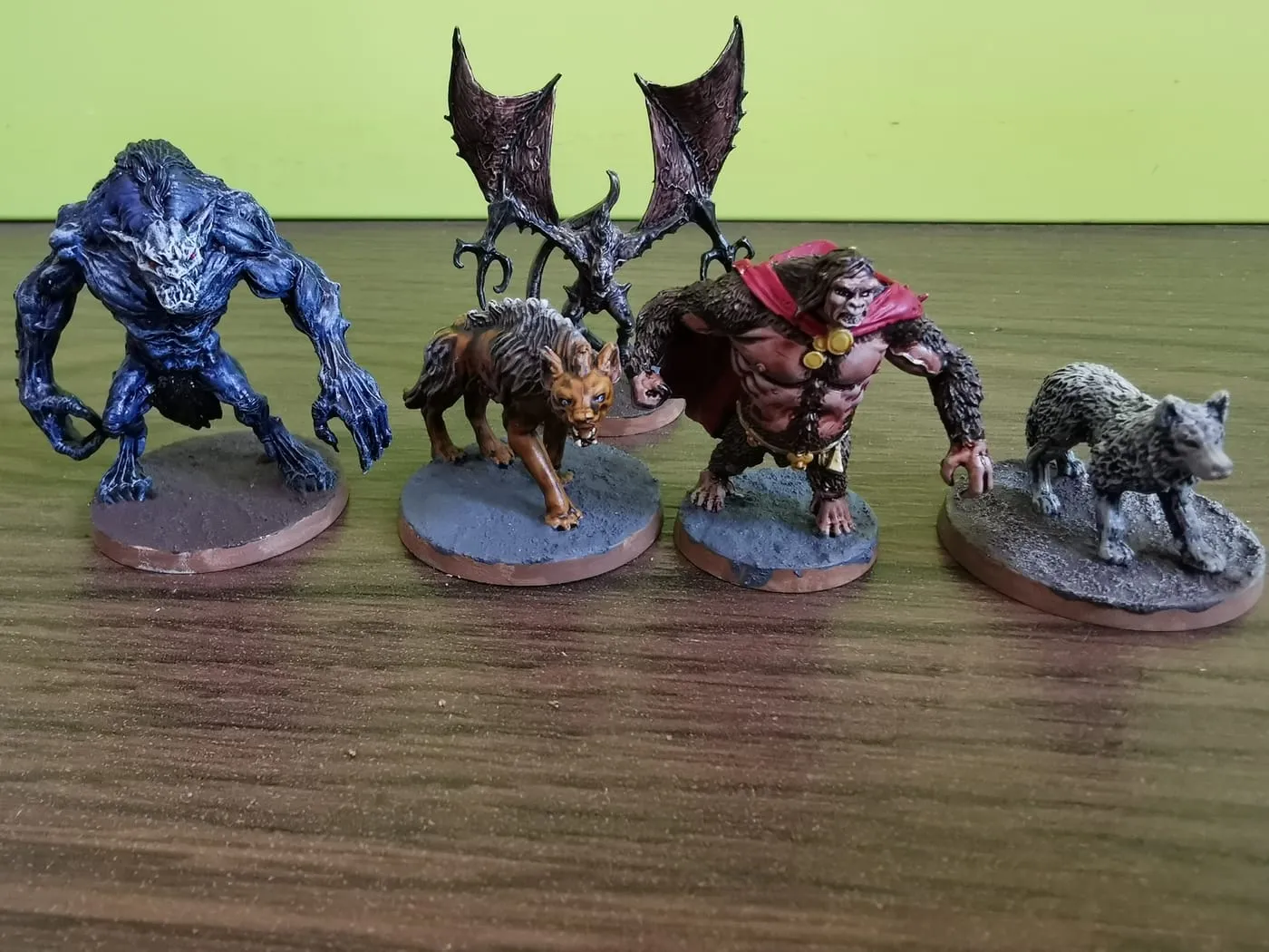 Painted monster miniatures: a blue demon, a giant bat, a hyena, an ape-man and a wolf