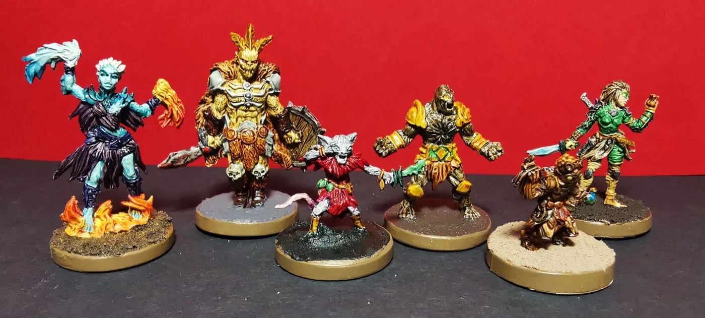 Six painted hero miniatures on gold-rimmed bases against a red background